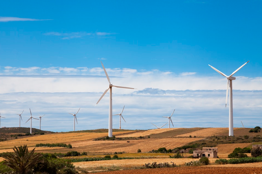 Várias turbinas eólicas em uma região rural e seca, com colinas